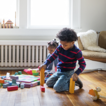 Kinder spielen mit Bauklötzen vor Heizung