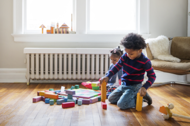 Kinder spielen mit Bauklötzen vor Heizung