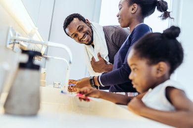 Eine dreiköpfige Familie beim gemeinsamen Zähneputzen im Badezimmer. 