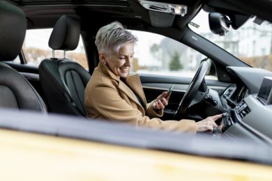 Eine Frau sitzt in ihrem E-Auto und bedient die Heizung.