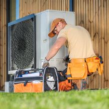 Ein Monteur installiert eine Wärmepumpe. 