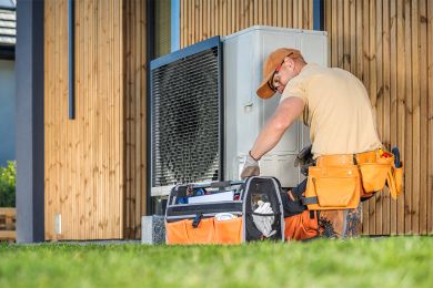 Ein Monteur installiert eine Wärmepumpe. 