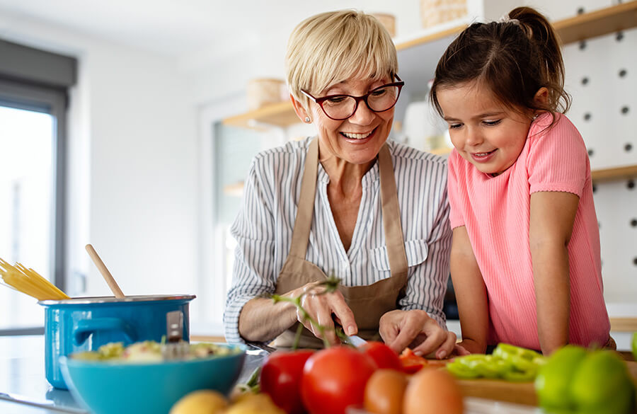 Oma und Enkelin bereiten in der Küche gemeinsam Gemüse zu.