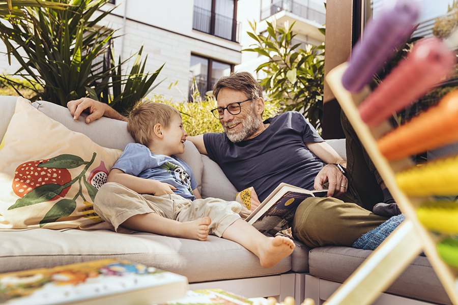 Großvater und Enkel lesen zuhause zusammen in einem Buch.